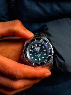 a close up of a person adjusting their Rolex watch on their wrist