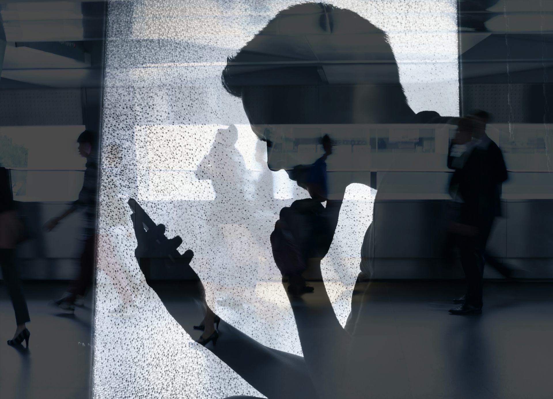 L'ombra d'un xic mirant la pantalla d'un mòbil.