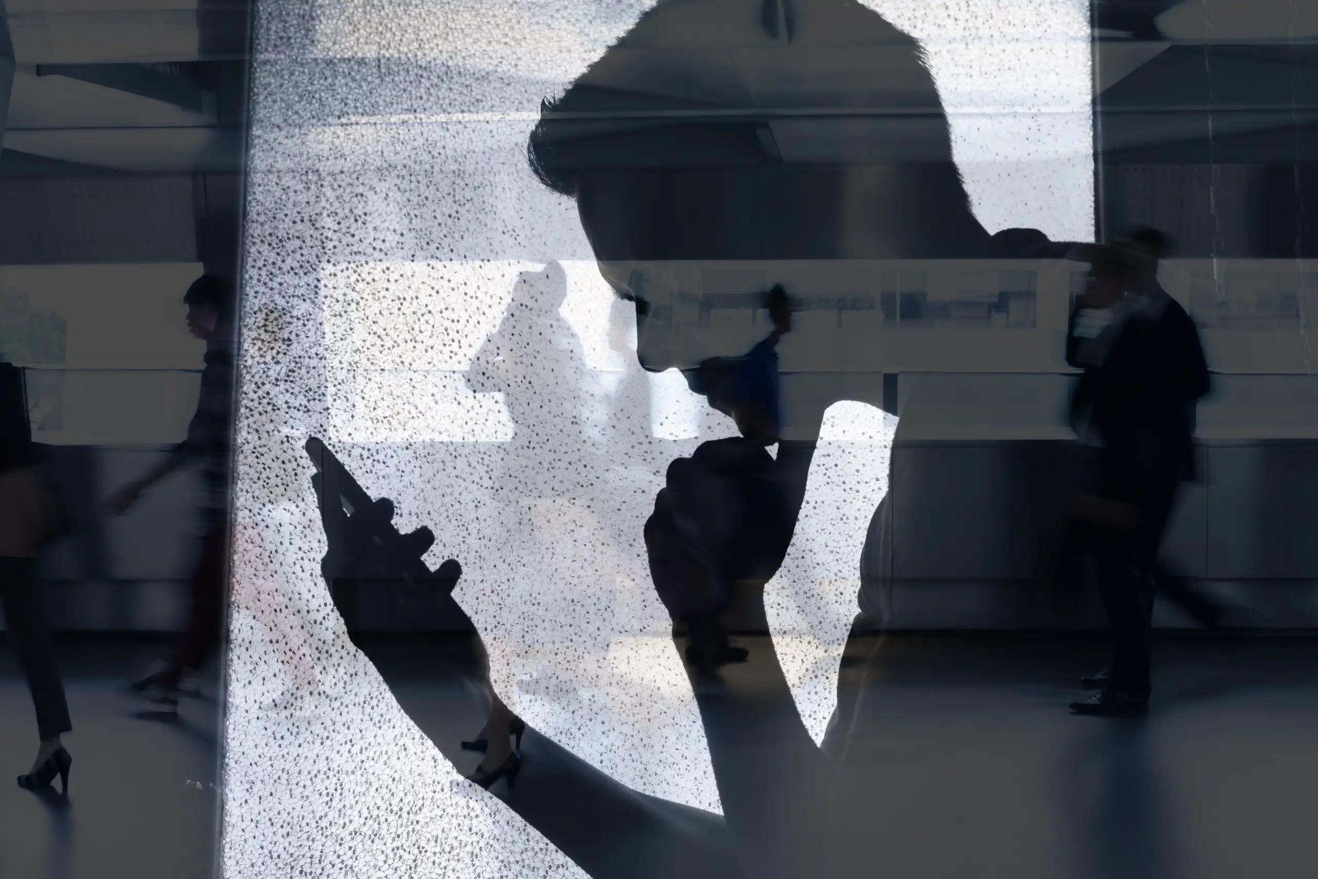L'ombra d'un xic mirant la pantalla d'un mòbil.