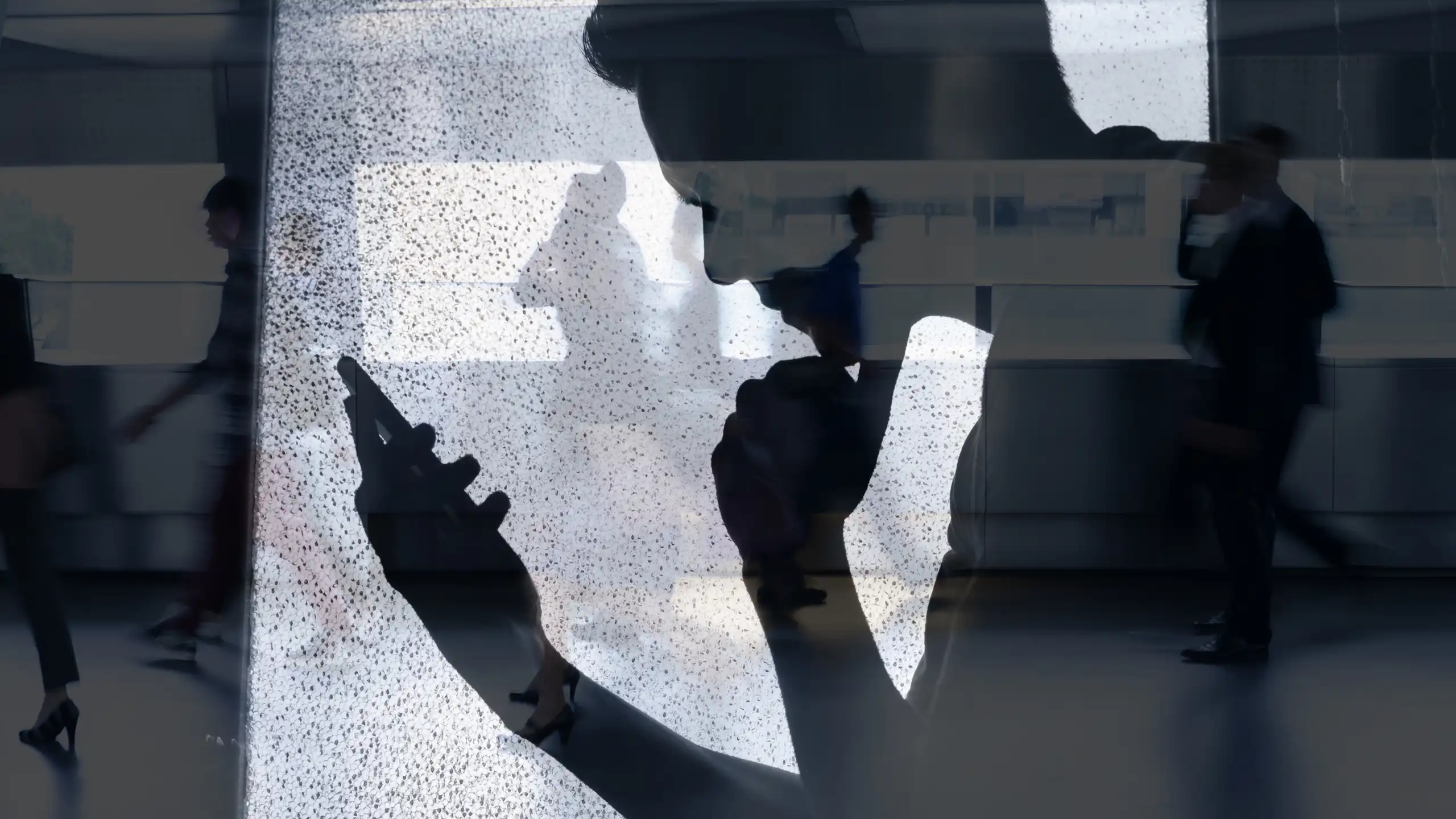 L'ombra d'un xic mirant la pantalla d'un mòbil.