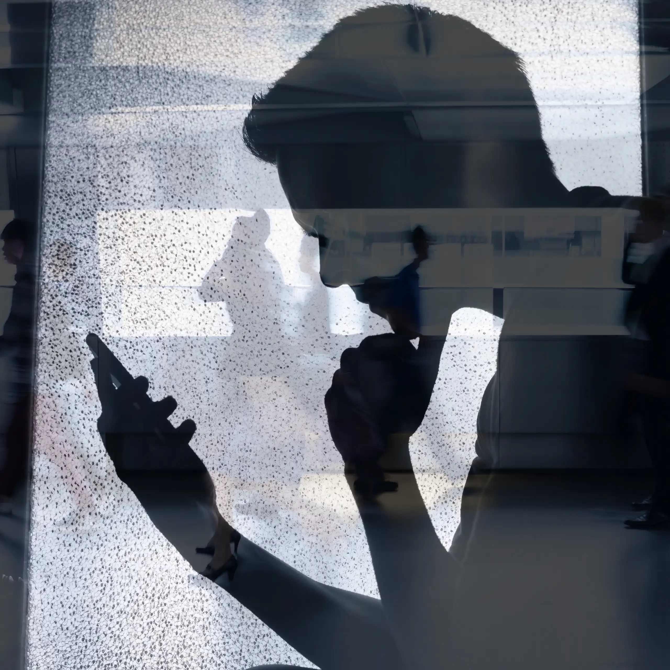 L'ombra d'un xic mirant la pantalla d'un mòbil.