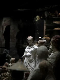 A Roman statue sits in a dimly lit museum.