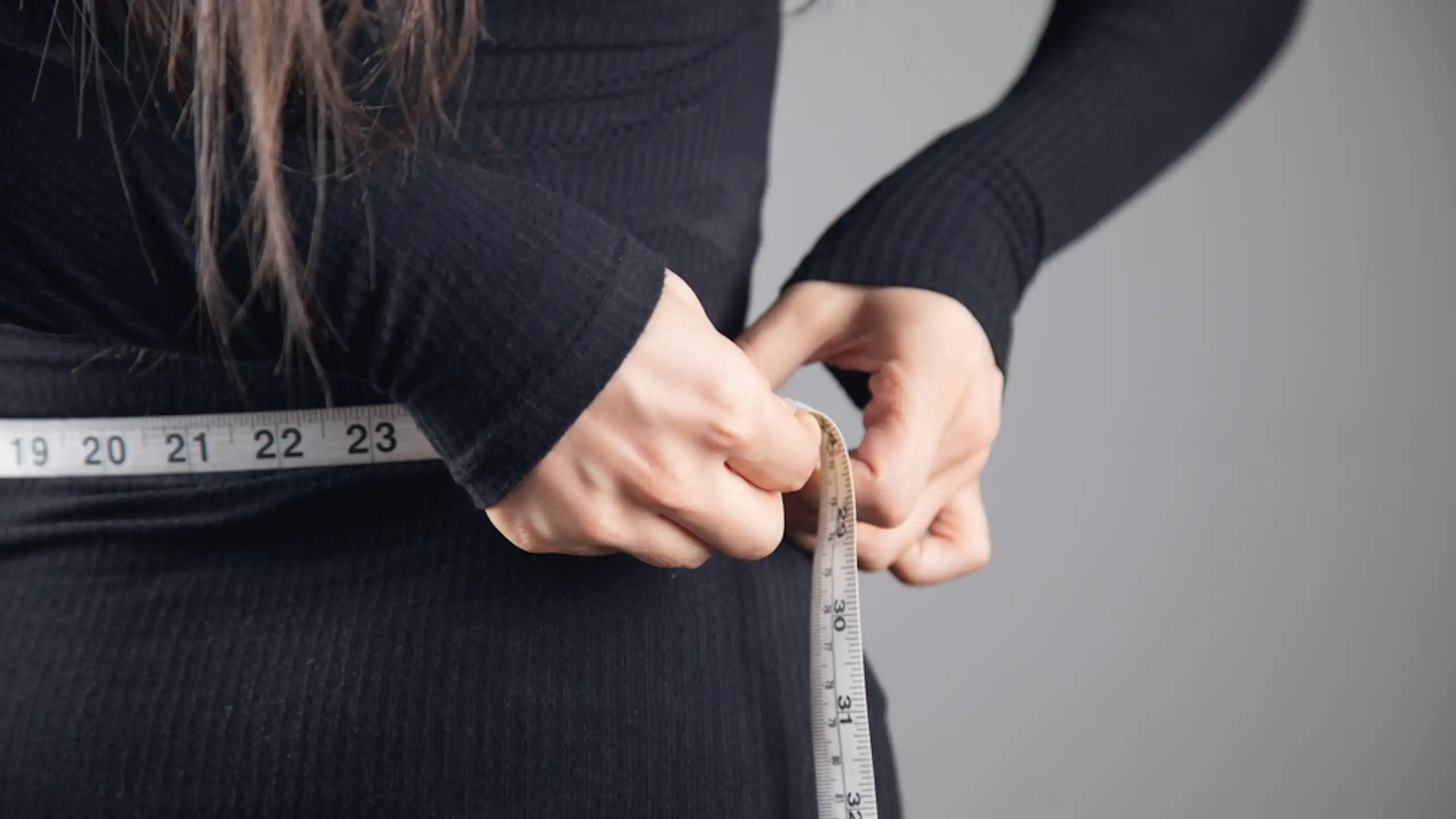 Une femme mesurant sa circonférence abdominale.
