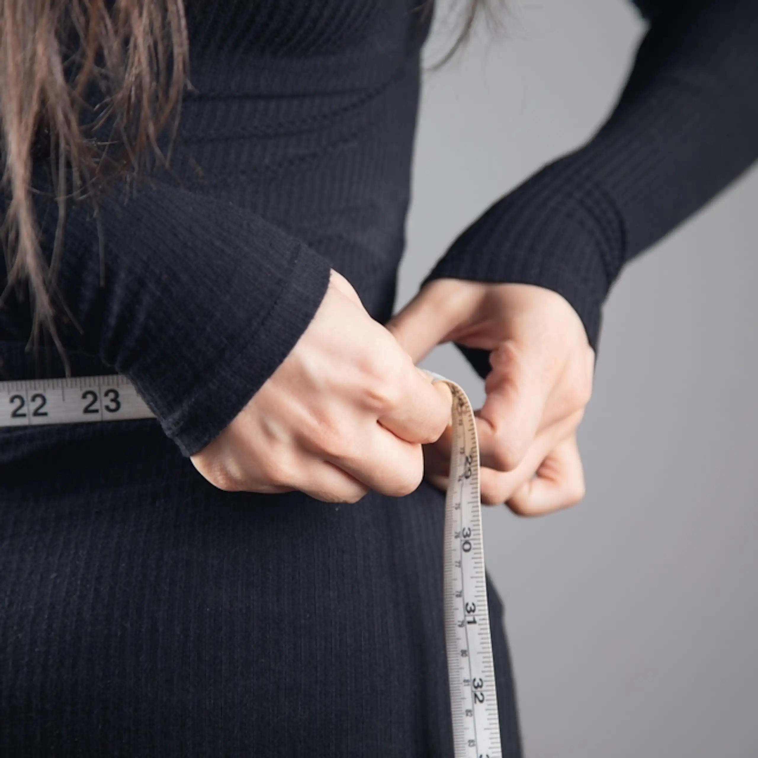 Une femme mesurant sa circonférence abdominale.