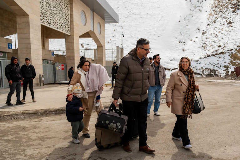 An Iranian family with luggage walk away from the border crossing into Turkey.