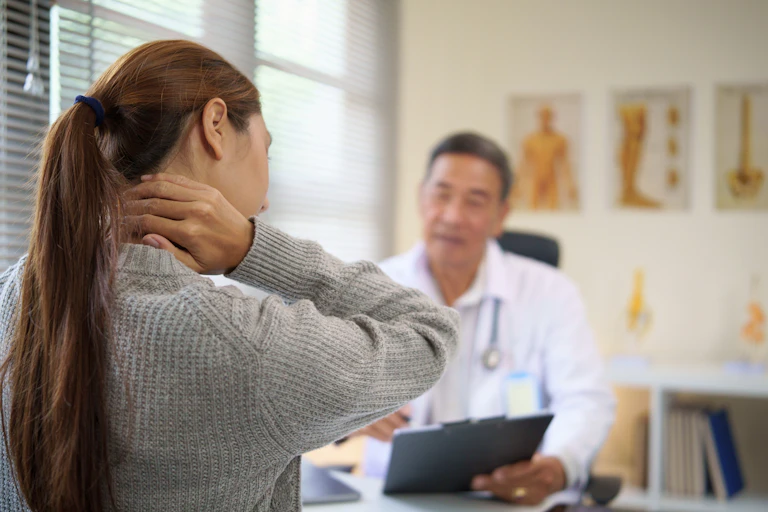 Woman at doctors holding neck in pain.