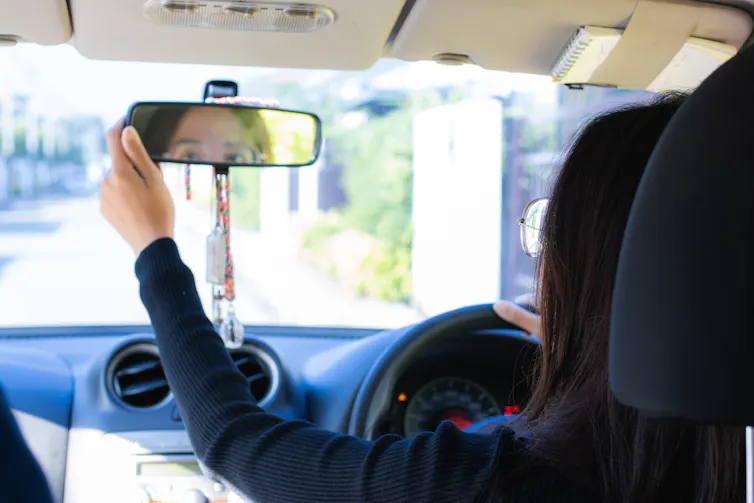 woman checking in rear-view mirror of her car.