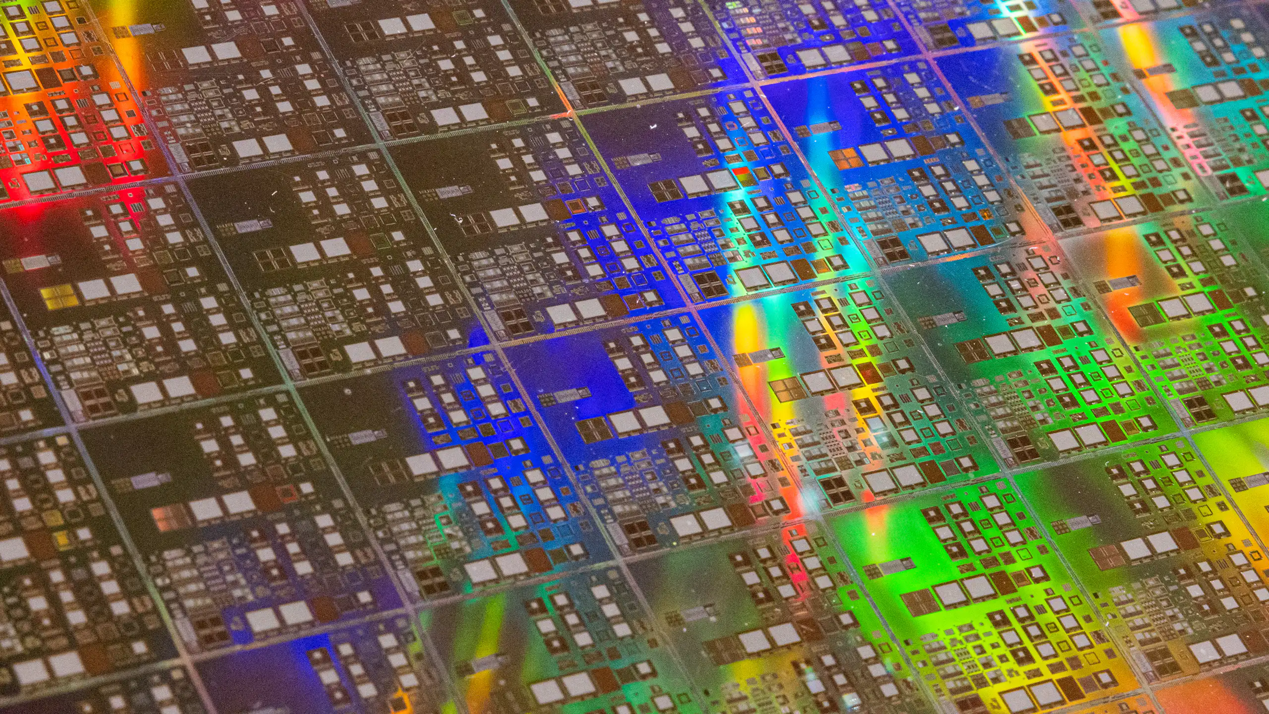 an irridecent rainbow pattern reflects off a shiny surface covered with repeated patterns of rectangles of various sizes