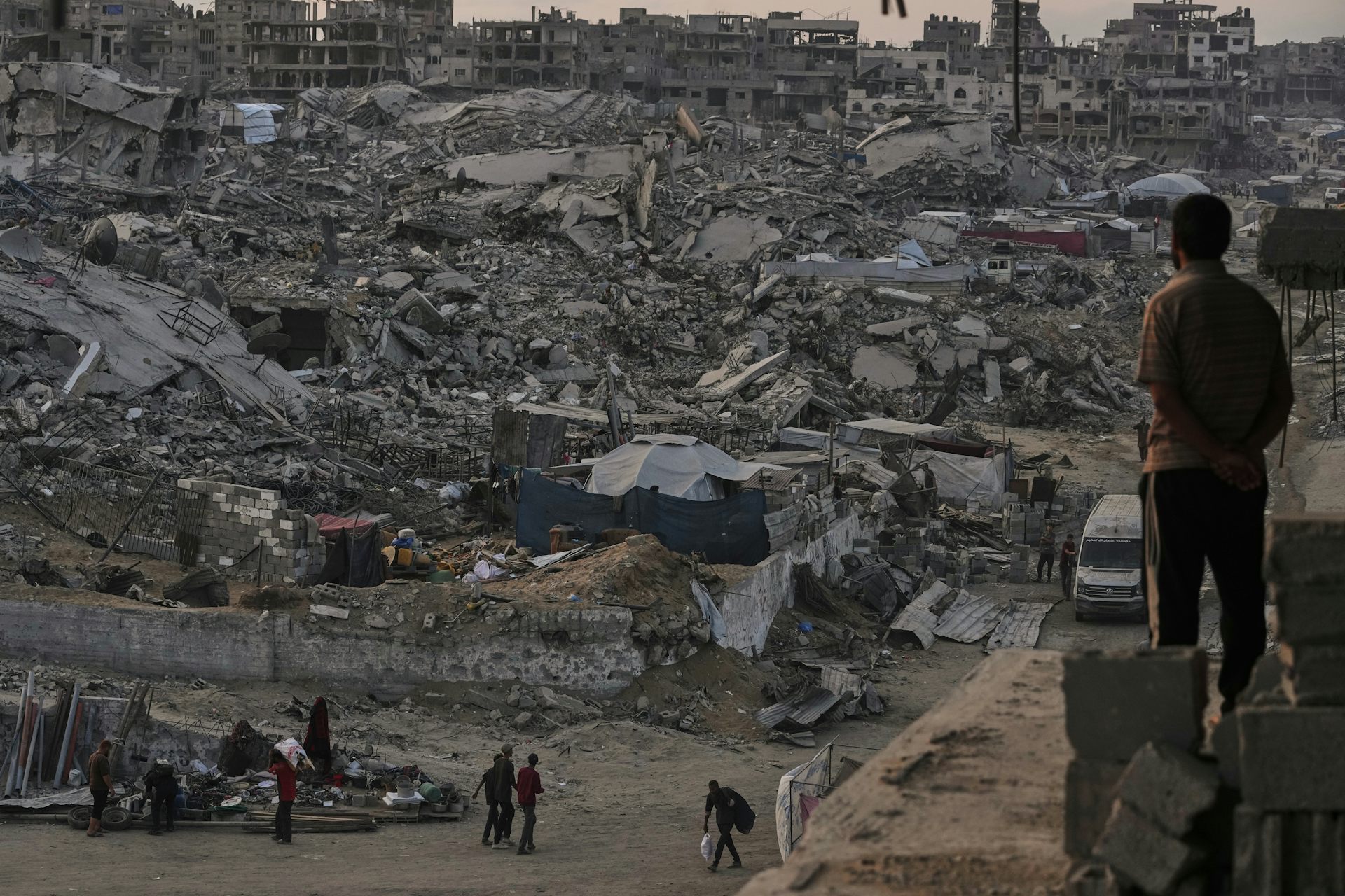 La gente se encuentra entre las ruinas de una zona residencial destruida.