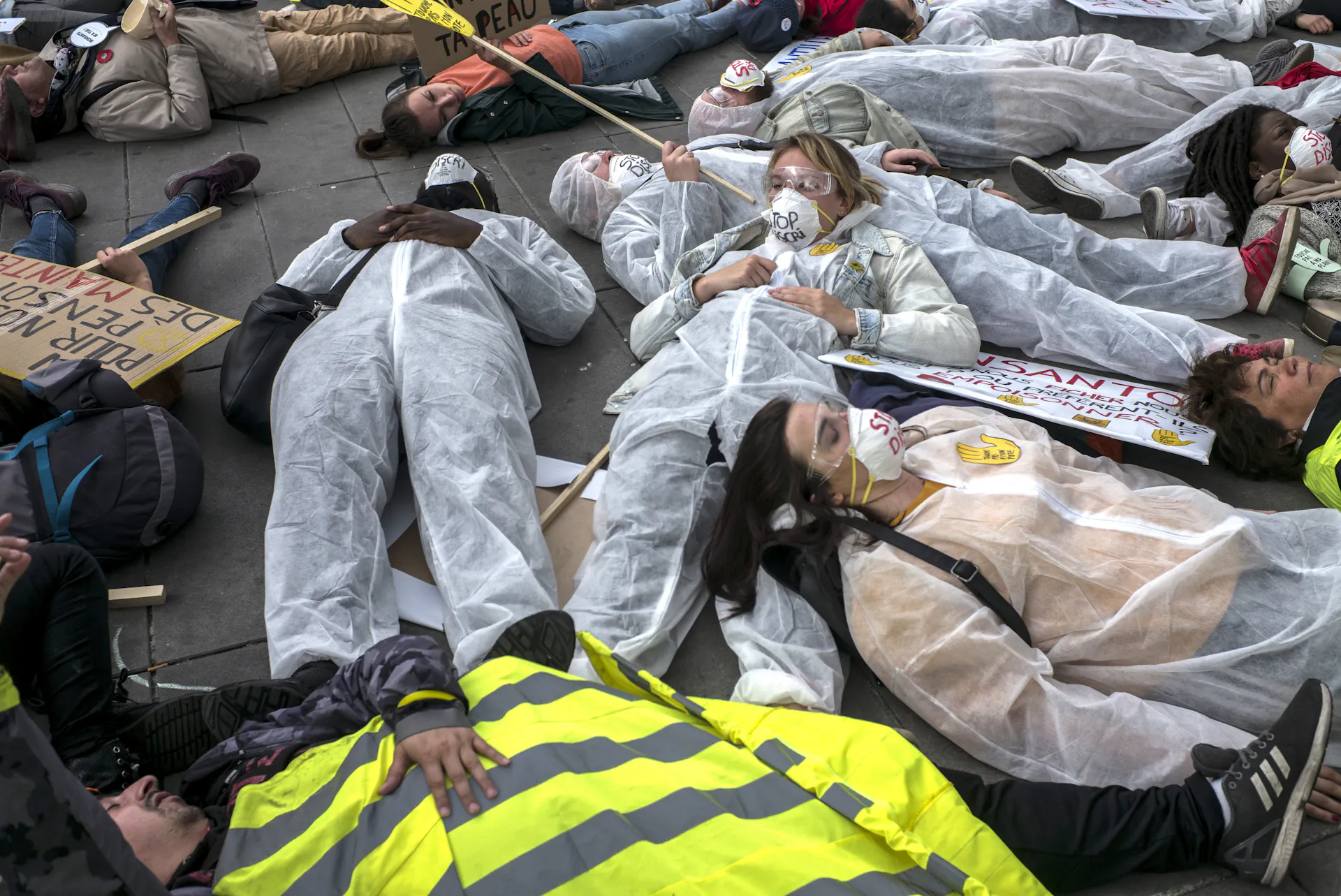 People wearing protective clothing lie down in the street.