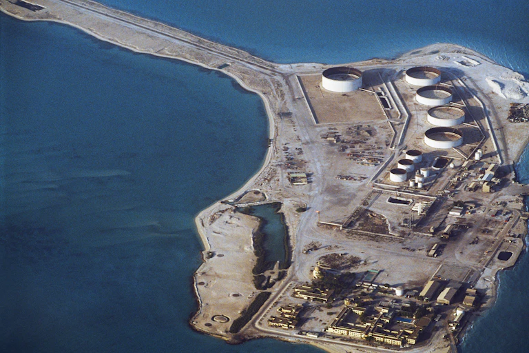 Birds-eye view of an oil refinery surrounded by water.
