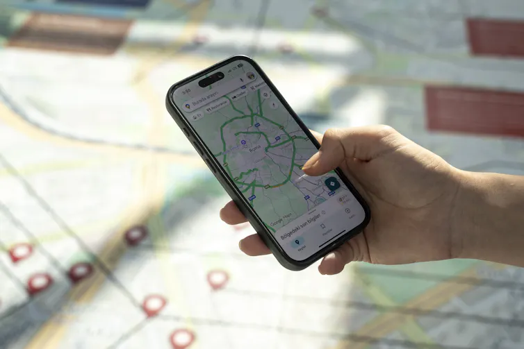 a hand holds a smartphone displaying a map with a map in the background