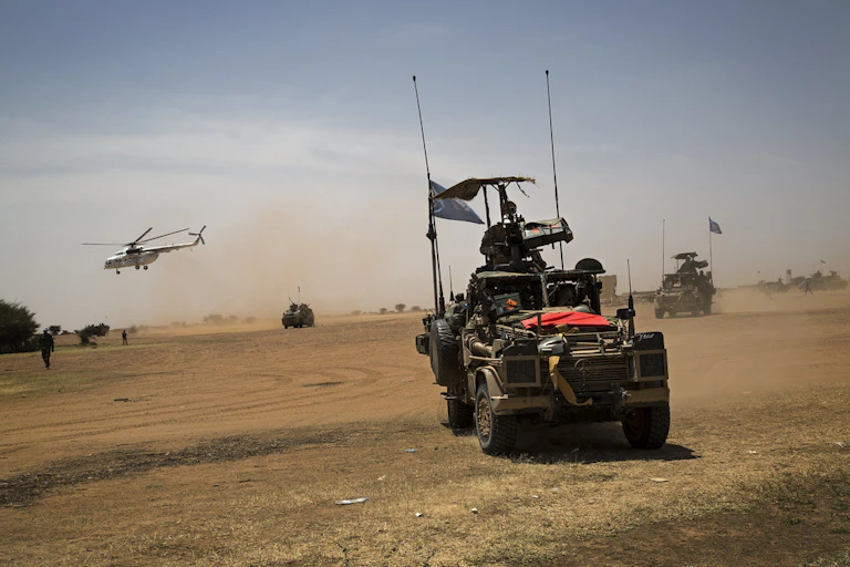 Military vehicles and helicopter in desert setting