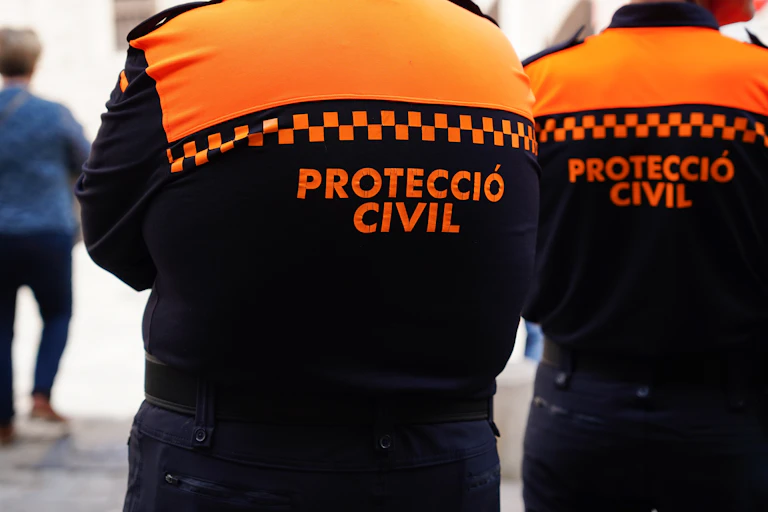 Dos tècnics de protecció civil, d'esquena.