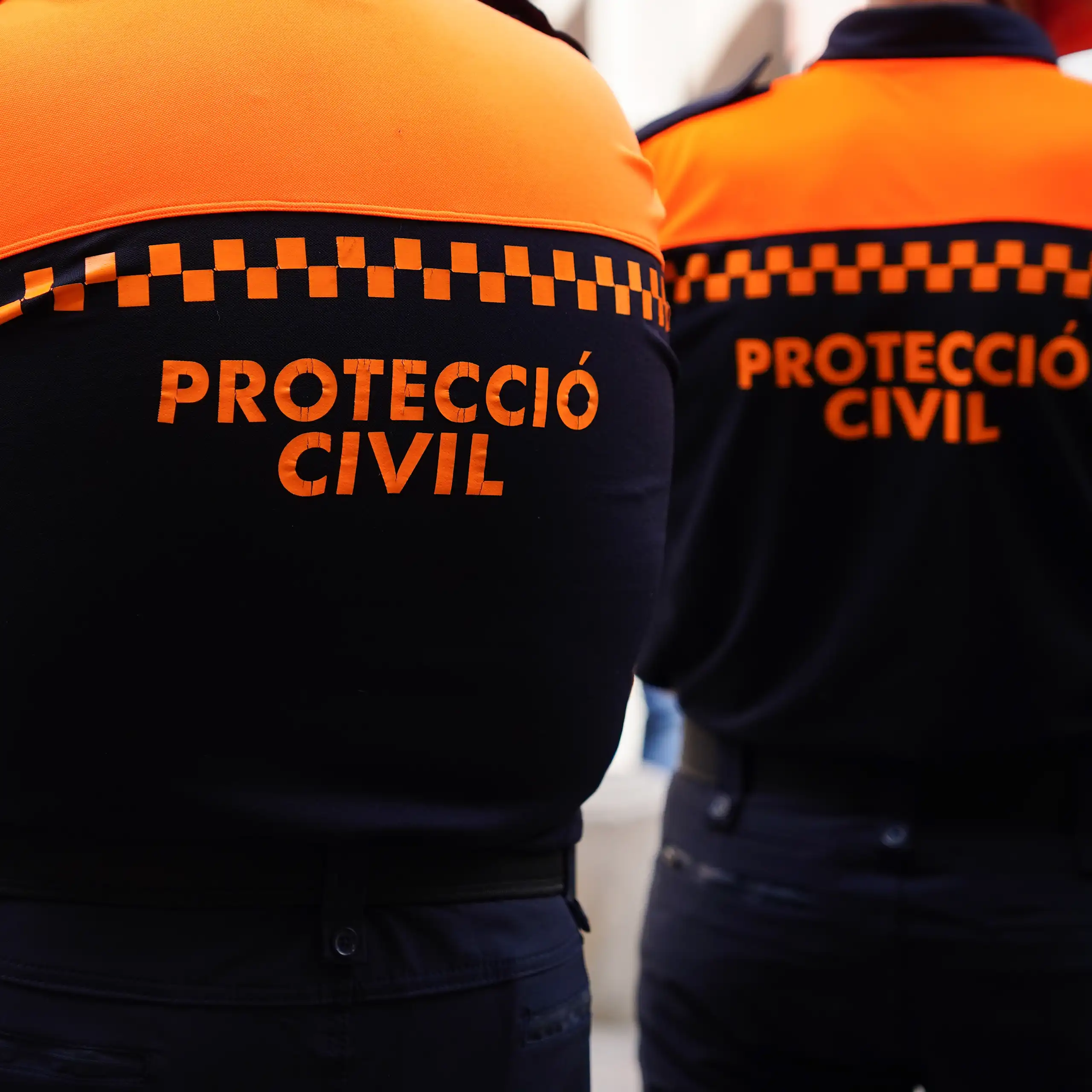 Dos tècnics de protecció civil, d'esquena.