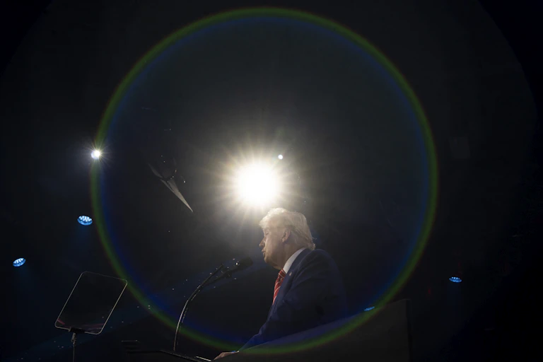 A light shines on a man speaking at a lectern on stage.