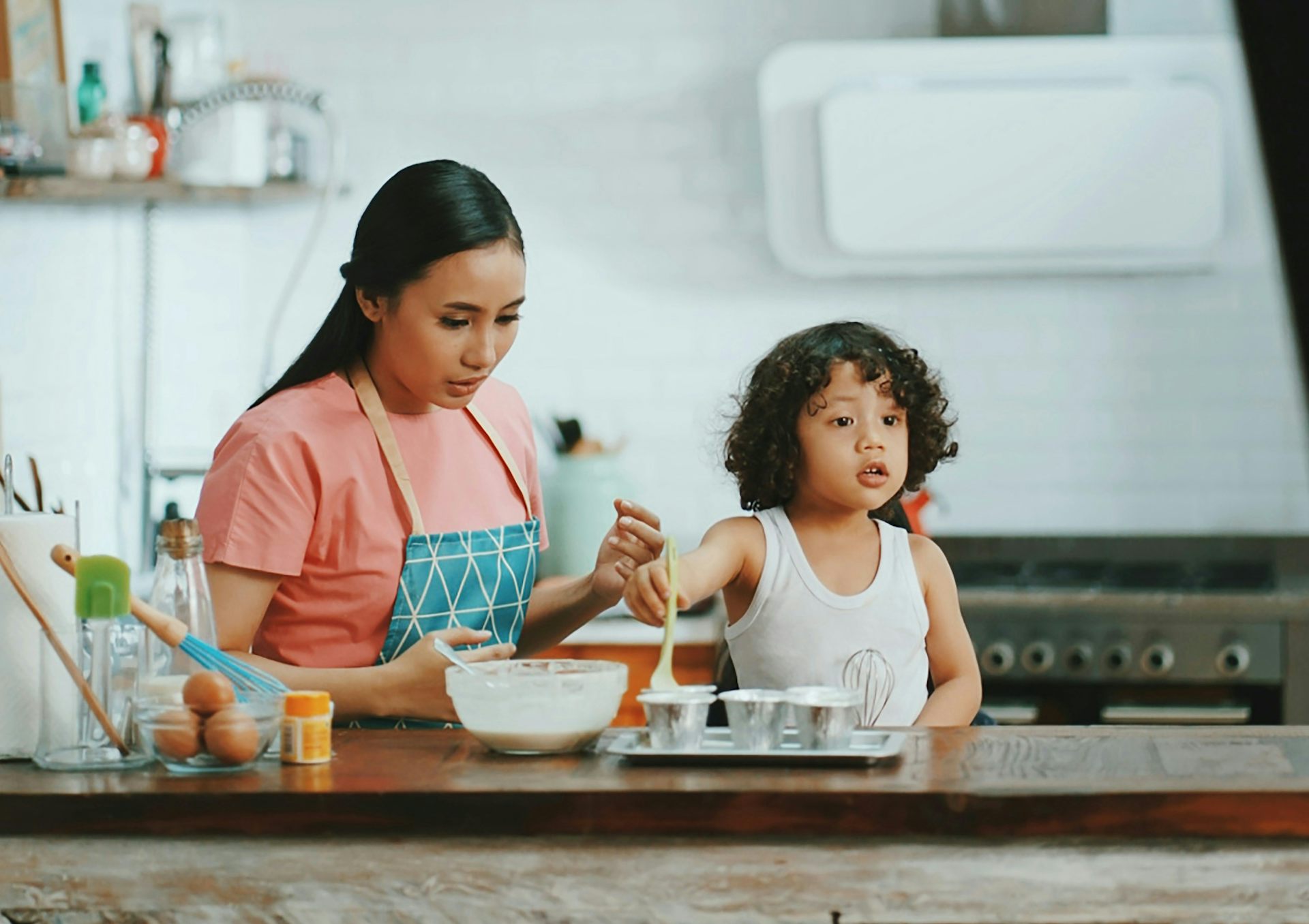 Una mujer hornea con un niño en la cocina.