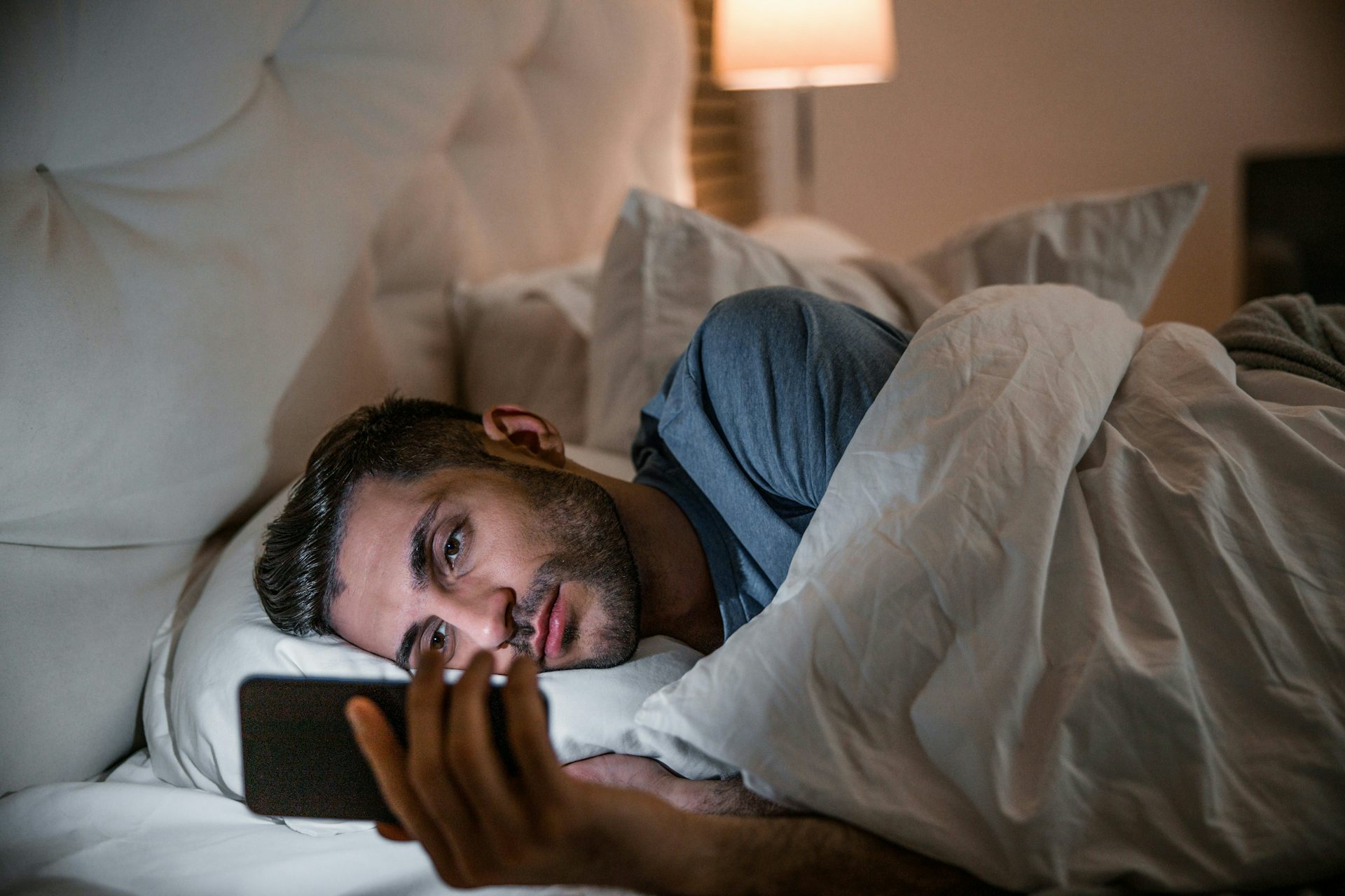 Un hombre al lado mira su teléfono en la cama.