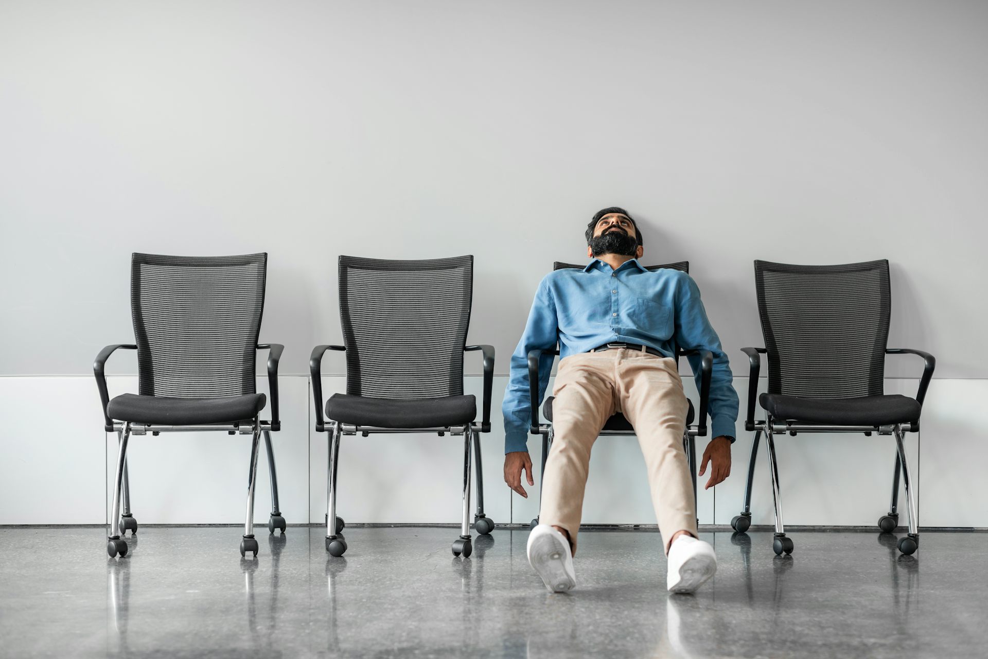 Bored man sitting back on row of chairs.