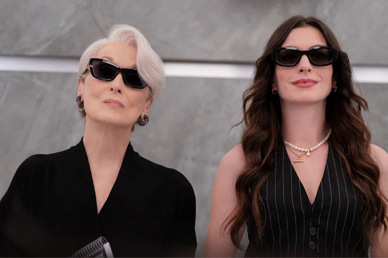 Two women dressed in black wearing sunglasses.