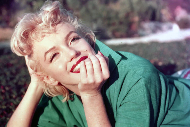 Monroe lying on the grass in a green shirt, smiling.