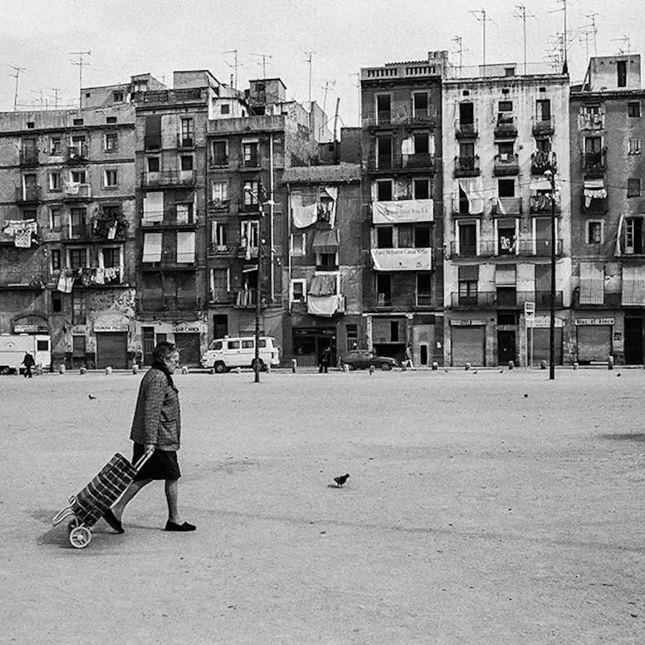 Una dona camina pel carrer davant d'edificis antics en una imatge en blanc i negre.