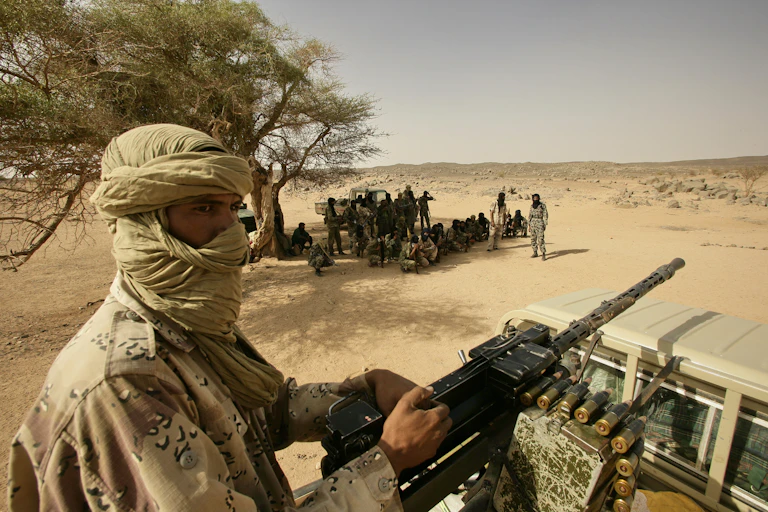 Armed men in military uniform in an arid landscape