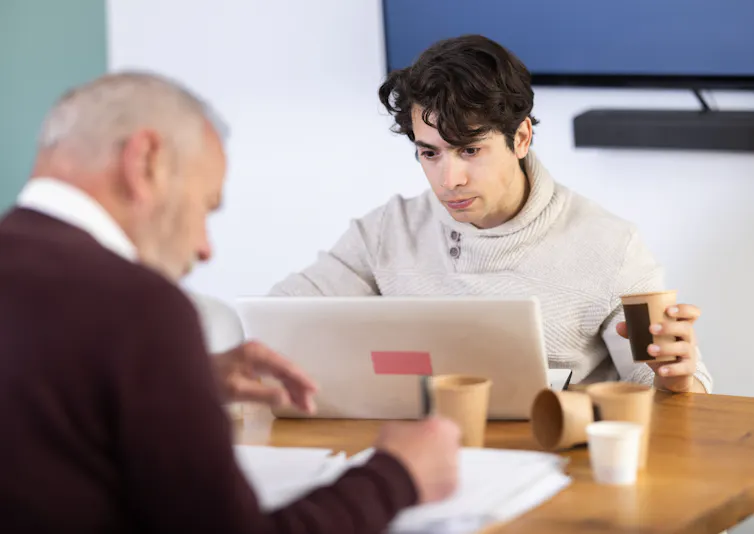 Younger and older man working at table