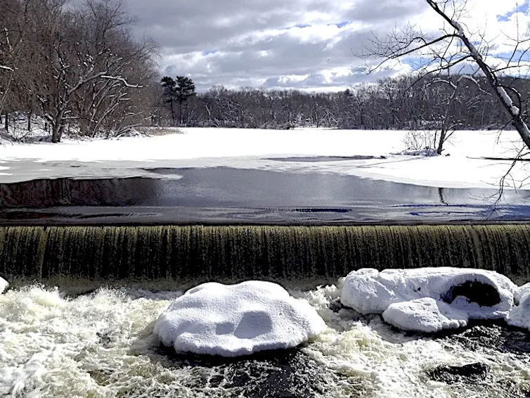 A small dam with water from a river spilling over it.