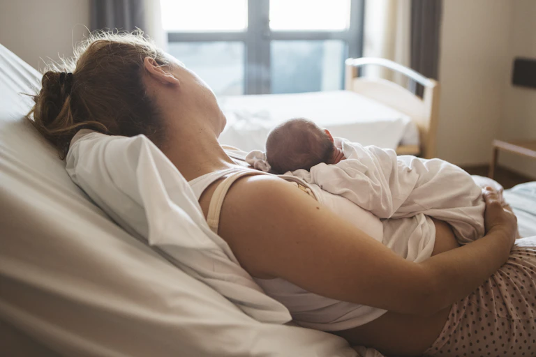 Woman holds a baby after giving birth