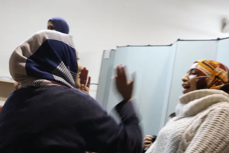 Two women wearing hijabs are seen in a staged altercation.