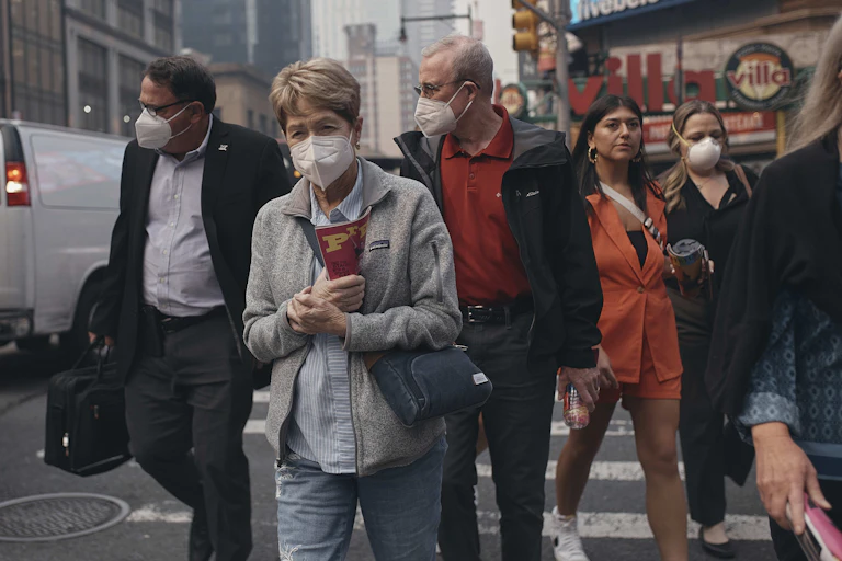 People walk along a city street wearing masks