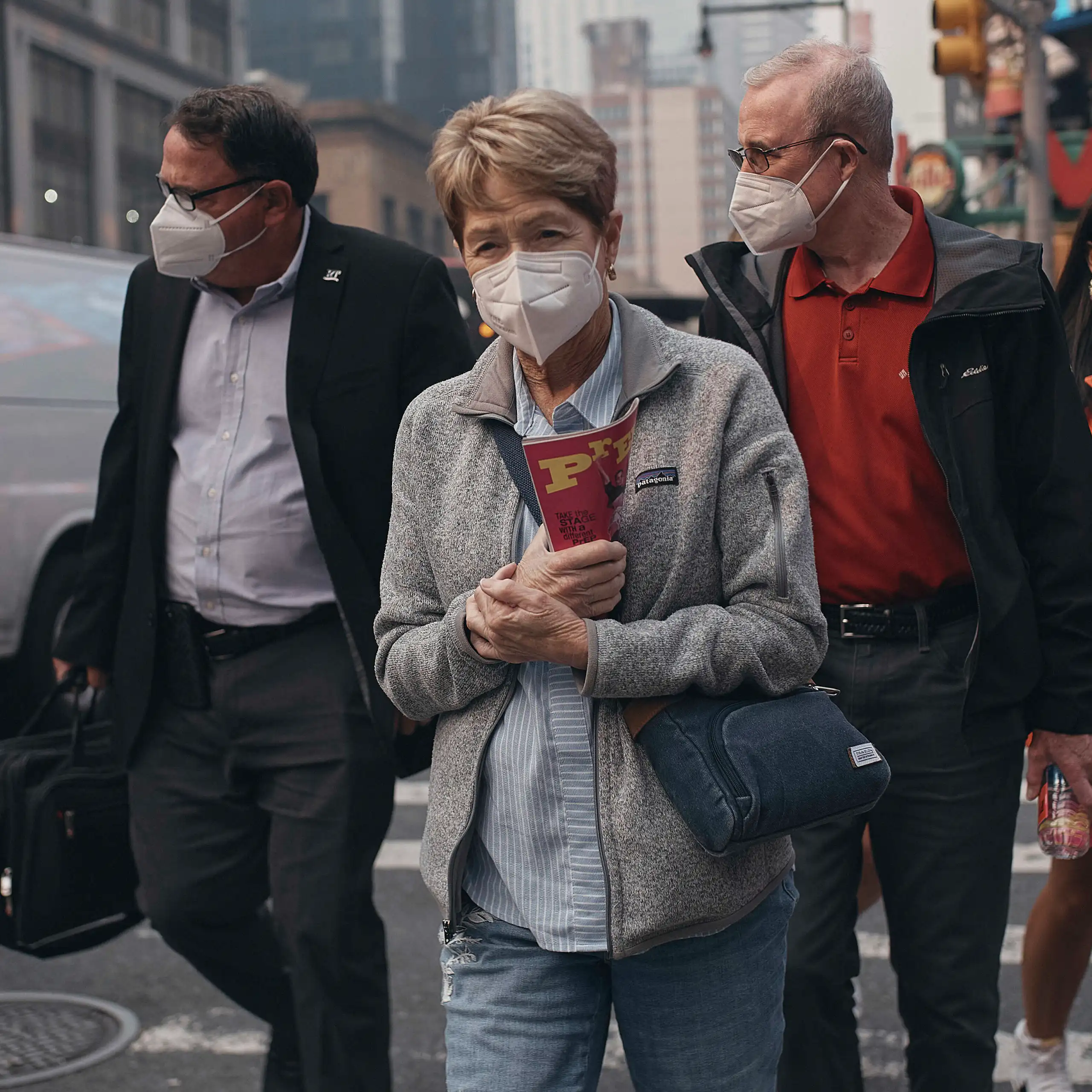 People walk along a city street wearing masks