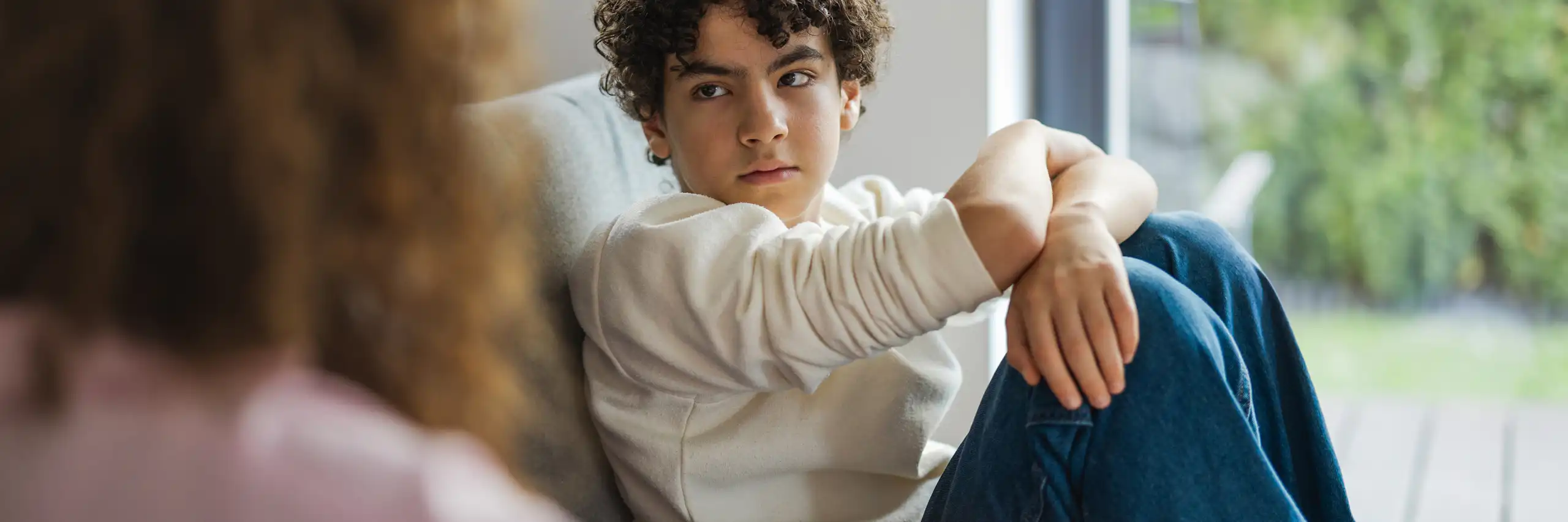 Un garçon assis sur un sofa regarde sa mère avec intensité.