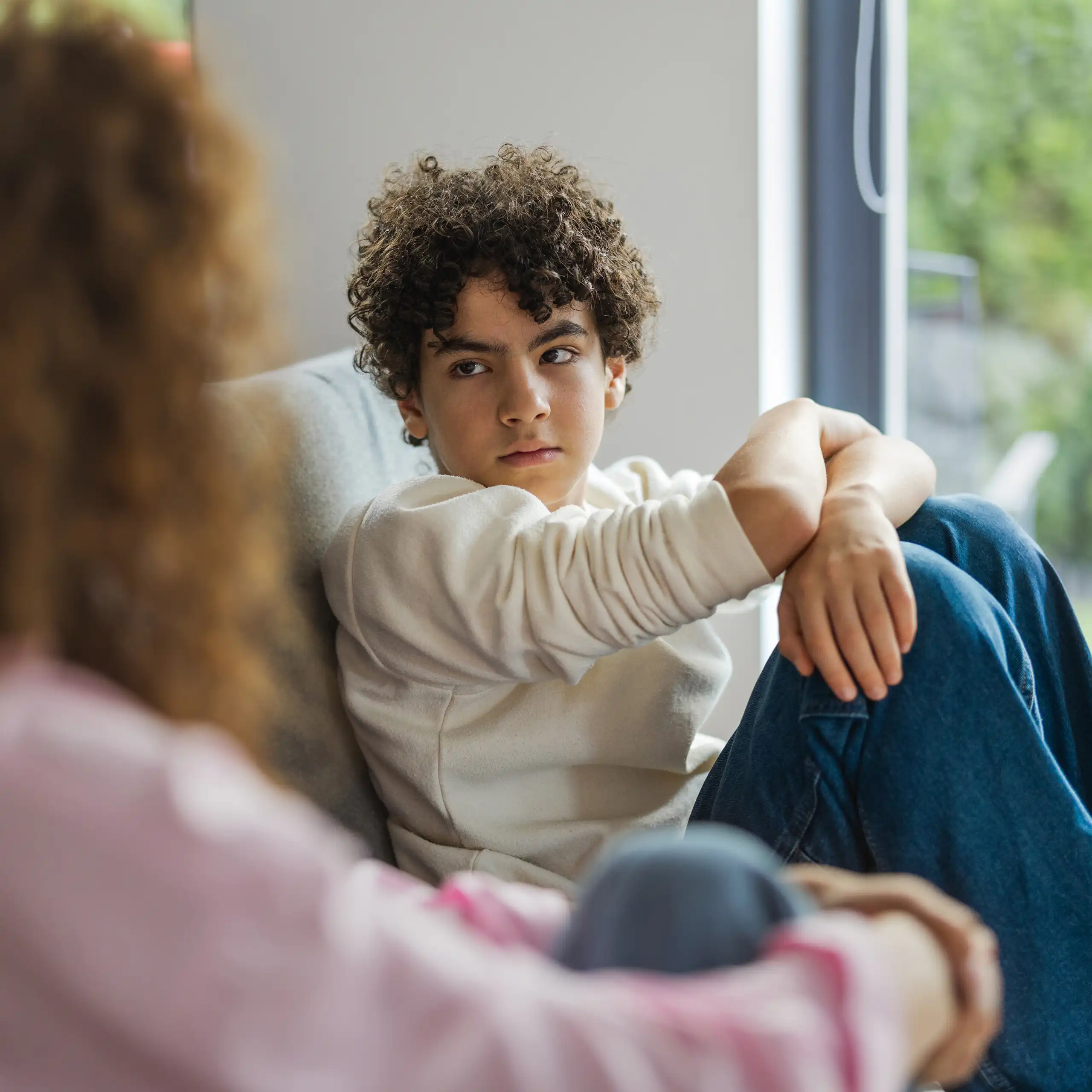 Un garçon assis sur un sofa regarde sa mère avec intensité.