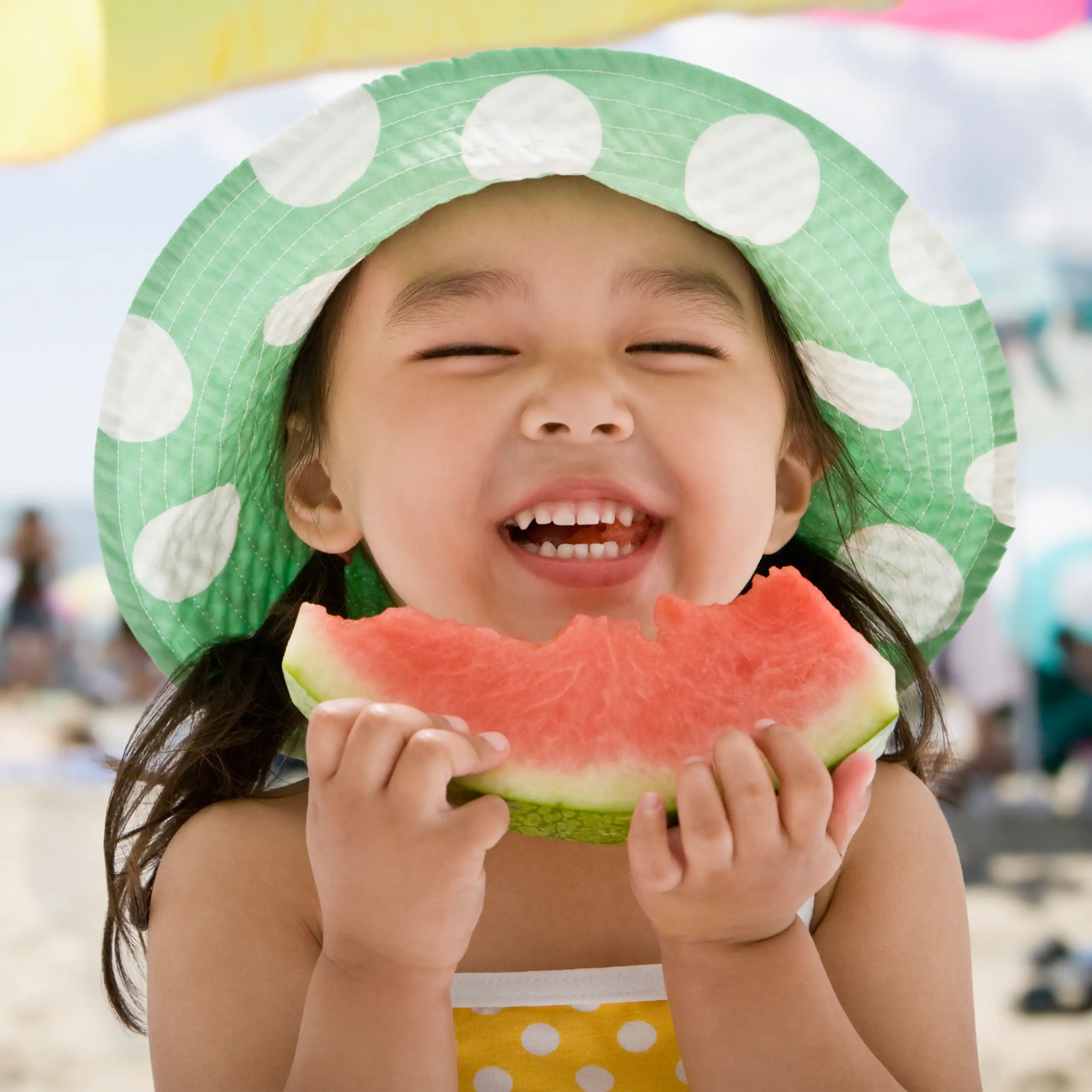 Une petite fille mange de la pastèque en souriant.