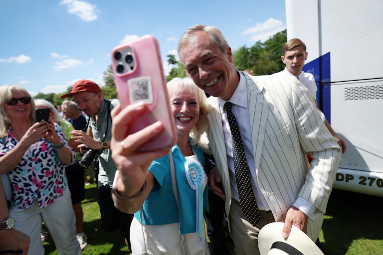 reform uk leader nigel farage posing for a selfie with a female supporter wearing a reform rosette