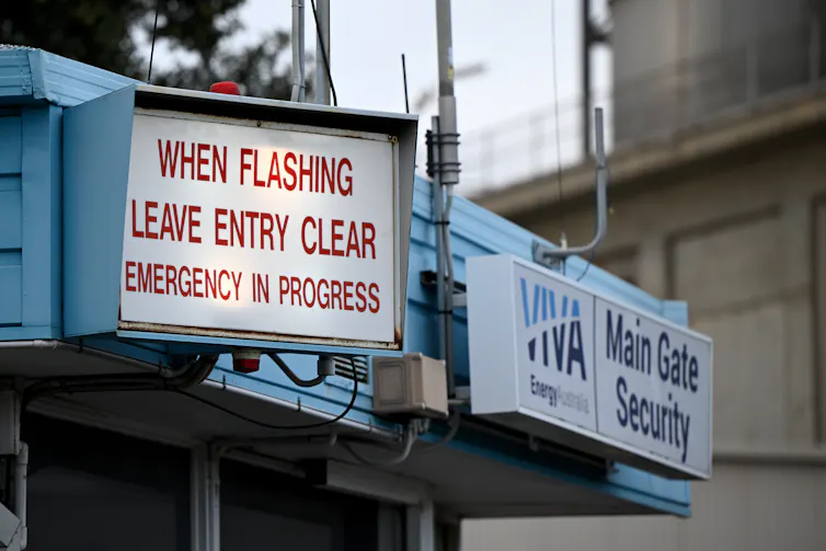sign warning of emergency in progress at oil refinery.