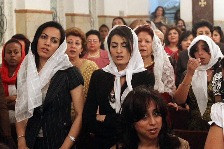 Group of women, some wearing veils on their heads, in a church building