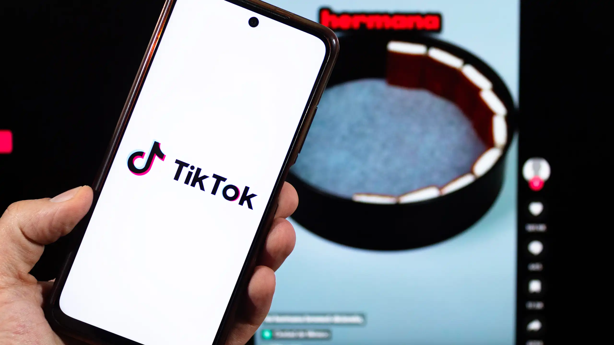 Pantalla de un móvil con el logotipo de TikTok y una imagen al fondo