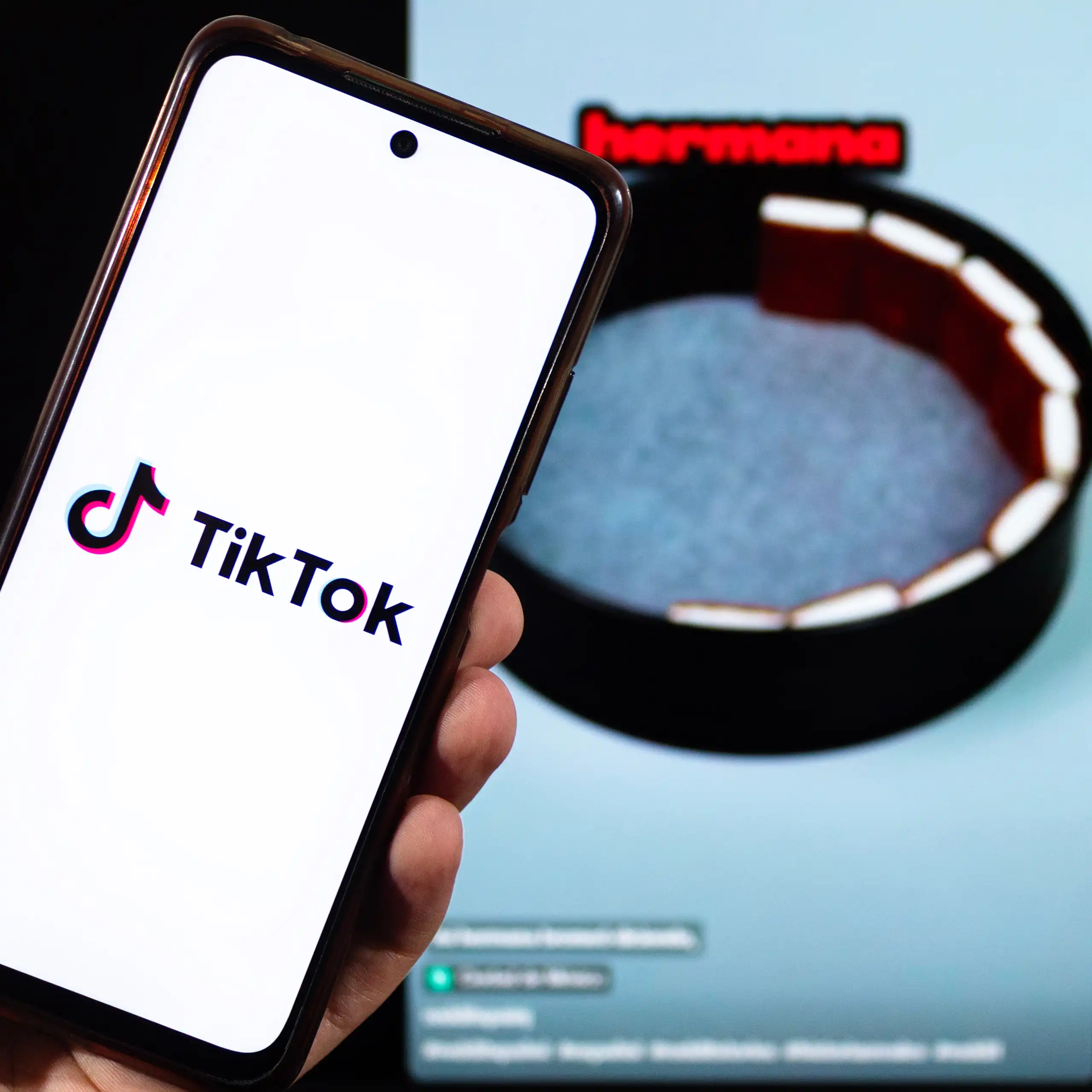 Pantalla de un móvil con el logotipo de TikTok y una imagen al fondo