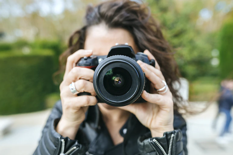 woman holds a camera up to her face to take a picture