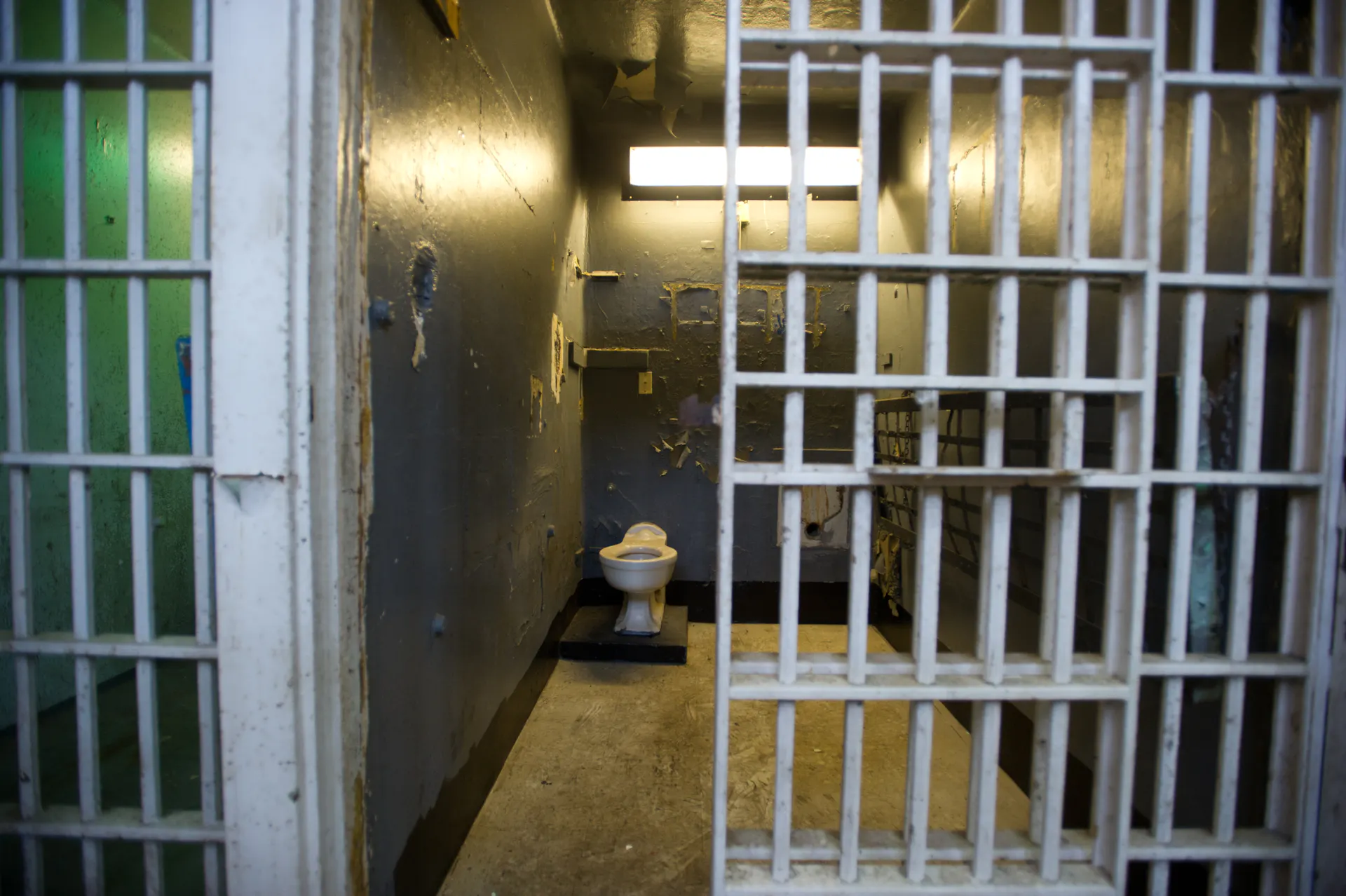 A prison cell is seen with it door partly open.