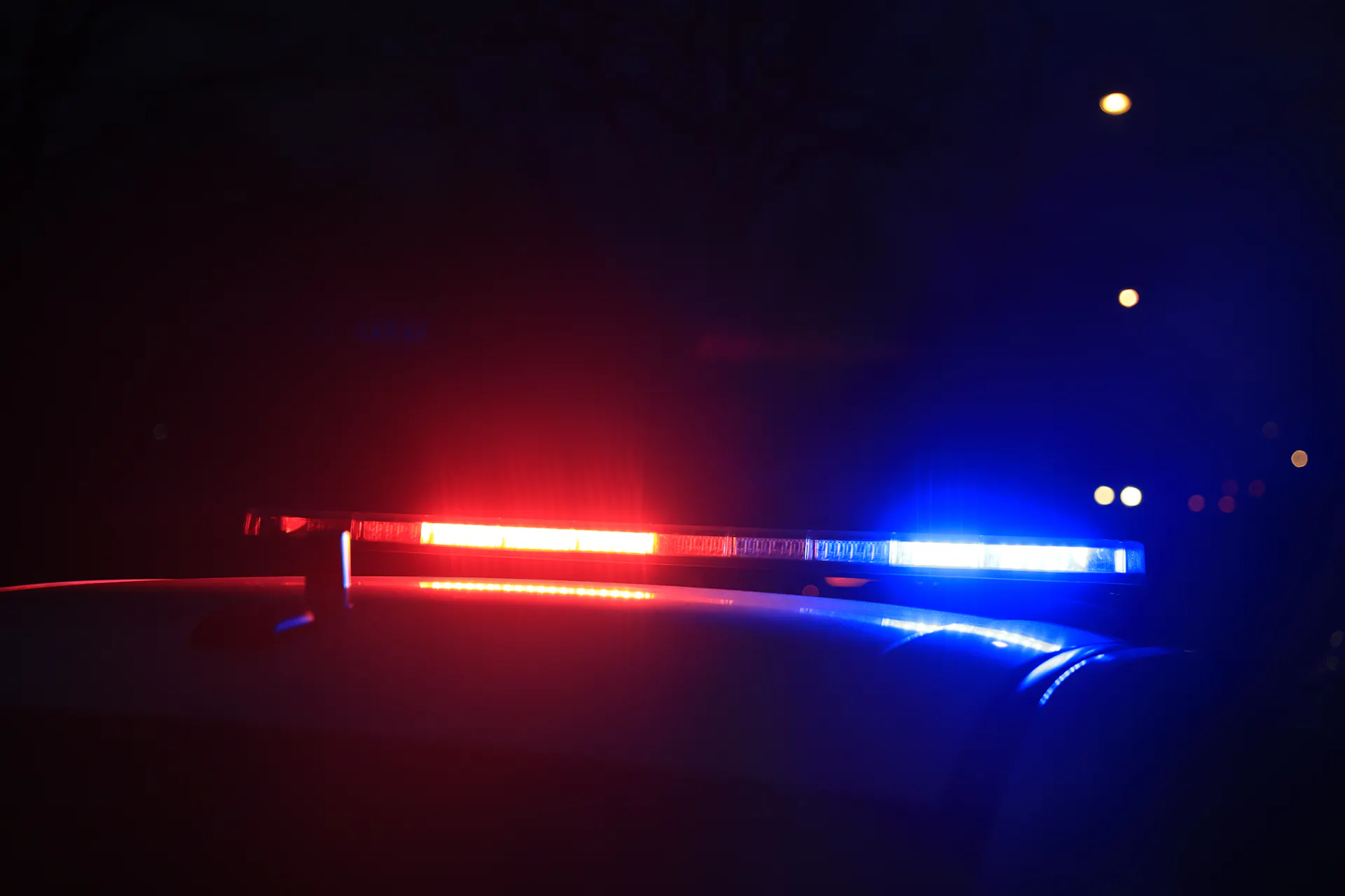 Flashing red and blue lights are seen on a police car at night.