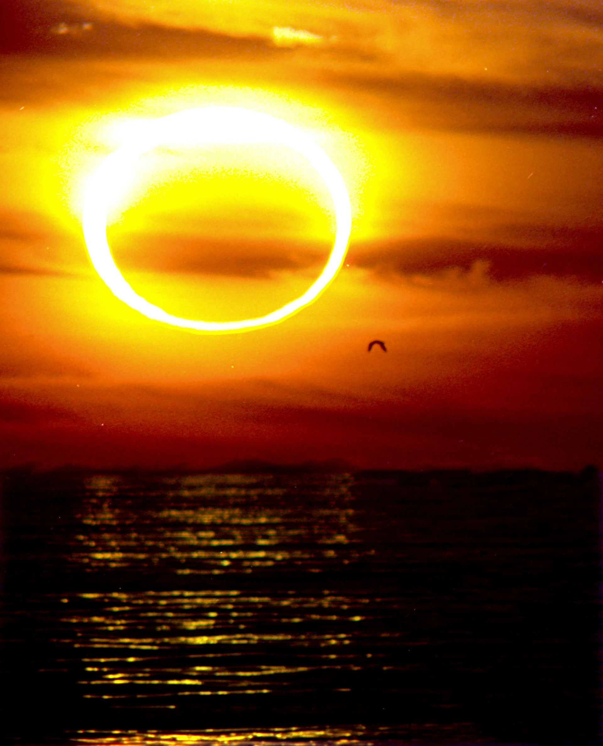 Eclipsi sobre el mar, amb el cel roig i taronja.