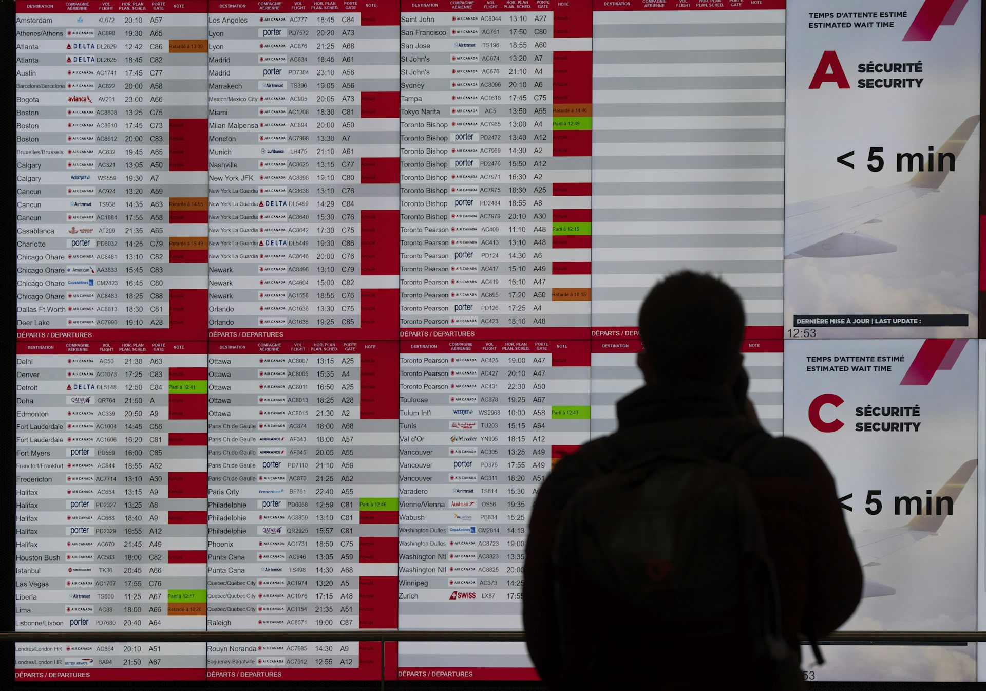 A traveller looks at a departure board filled with flight cancellations