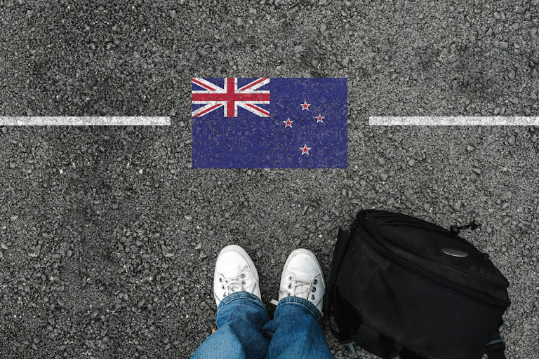 NZ flag on stoney ground with pair of shoes behind a white line