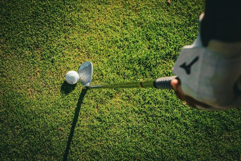A golfer looks down at a ball, ready to play a shot.