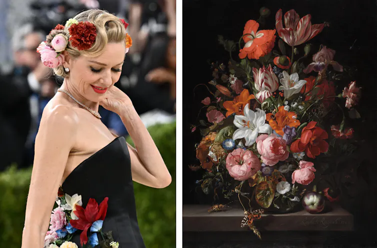Watts with flowers in her hair and on her dress; flowers in a vase.
