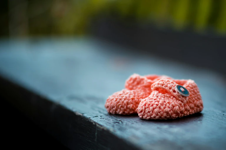 Pair of pink baby booties outside on bench